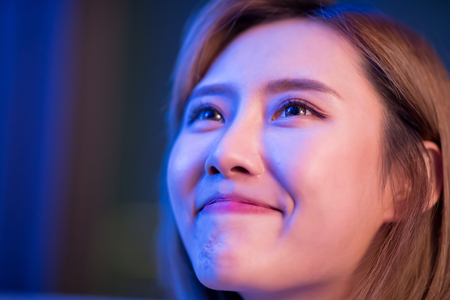 Young woman cry while watching a very moving movie at nightの写真素材