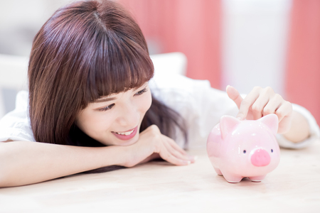 Happy woman look her pink piggy bank and feel happy at homeの写真素材