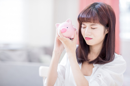 depressed woman with her pink piggy bank at homeの写真素材