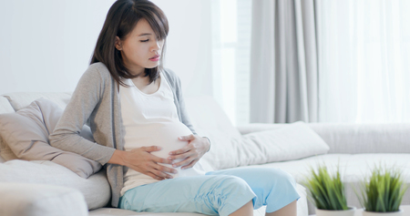 pregnant woman sit on the sofa and feel depressed at homeの写真素材