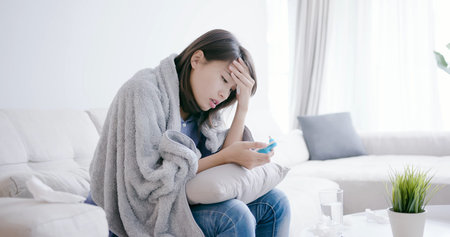 woman get sick and fever with thermometer at home