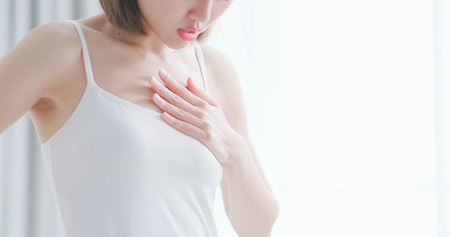 Beautiful young woman feeling sharp strong pain in the chest because of heart attackの写真素材