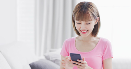 young woman use smart phone happily at homeの写真素材
