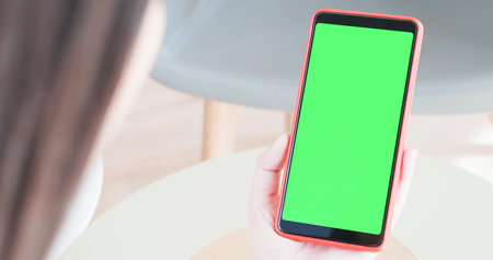 woman take cell phone with green screen in the cafe