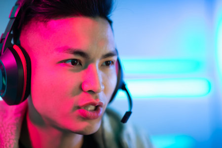 Young Asian Handsome Pro Gamer having live stream and playing in Online Video Game