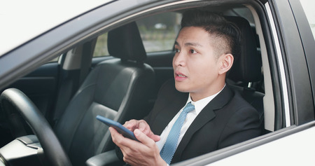 business man holding a phone and using the navigation system in the carの写真素材