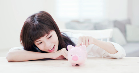 Happy woman look her pink piggy bank and feel happy at homeの写真素材