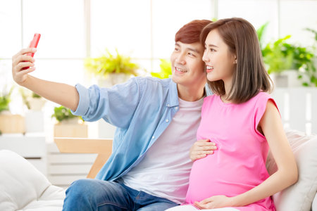 Young happy pregnant woman selfie with husband at home and expecting baby