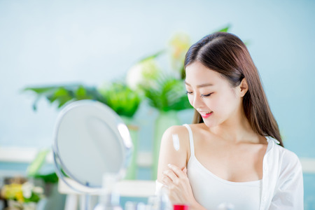 Young beauty asian woman apply sunscreen or lotion on her shoulder at homeの写真素材