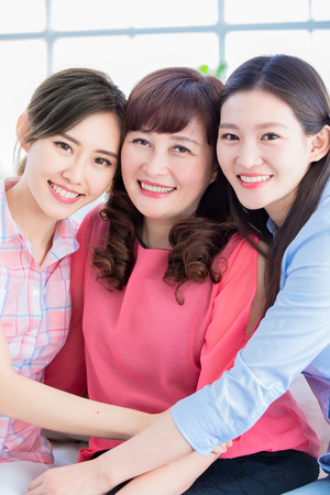 two daughter with her mother smile to you happily at homeの写真素材