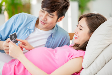 young pregnant woman with her husband looking  ultrasound photo and expecting the babyの写真素材