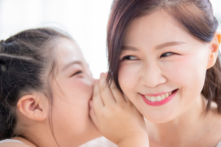 Daughter whisper to mom and mom smileの写真素材