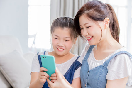 Daughters and mother use smart phone happily at home