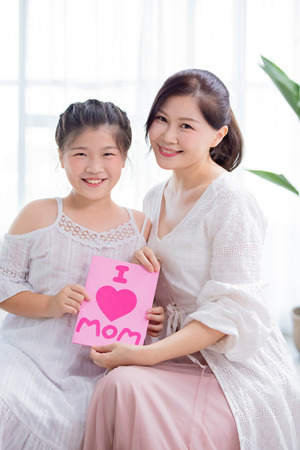 Daughter give card to her mom and mom smile happilyの写真素材