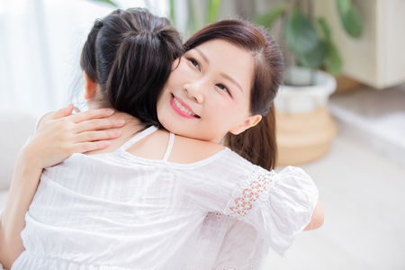 Daughter give mom a hug and mom smile happilyの写真素材