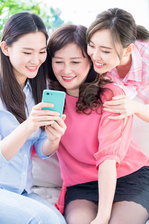 Daughters and mother use smart phone happily at homeの写真素材