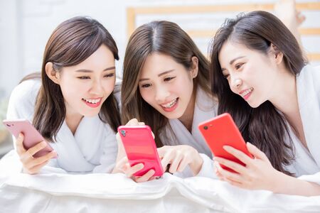 Smiling asian women wearing bathrobe are share something with the smart phoneの写真素材