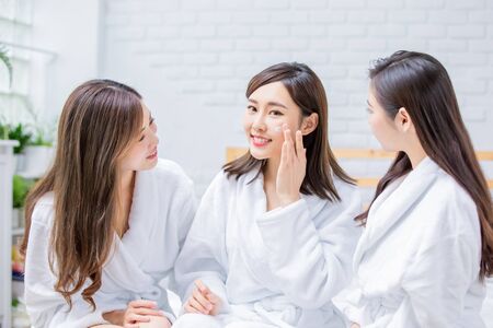 Smiling asian women apply cream on her face and feel goodの写真素材
