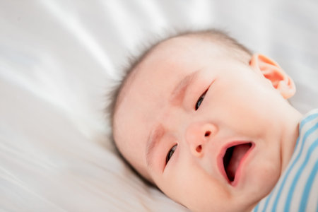 asian baby lying on the bed and cryingの写真素材