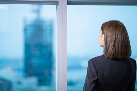 businesswoman look outside through the windor and ponderの写真素材
