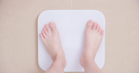 top view of woman stand on weight scale at home