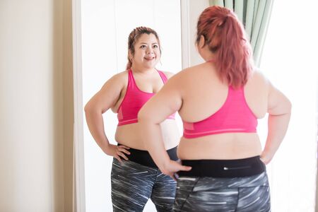 plus size sport asian girl look herself in the mirror and feel confidentの写真素材