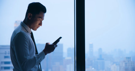 Asian businessman use cellphone and read message at night in the office