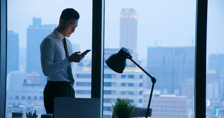 Asian businessman use cellphone at night in the office