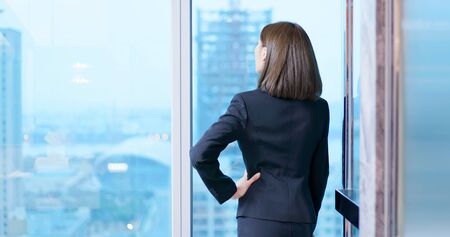 business woman gaze through the window thoughtfully and see outsideの写真素材