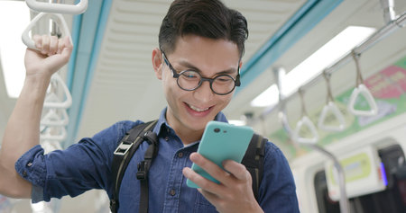 Young man take train or MRT and use the phoneの写真素材