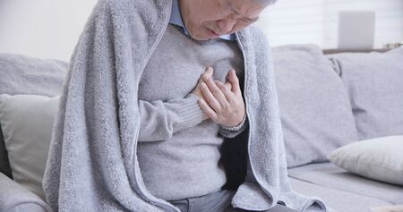 asian elderly sick man feeling sharp strong pain because of heart attackの写真素材