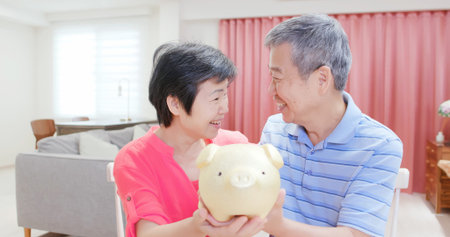 Good Retire plan concept - eldely couple hold piggy bank smile happily at homeの写真素材