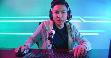 Young Asian Handsome vlogger having live stream and playing in Online Video Game