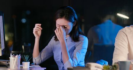asian businesswoman overtime work - she has a headache and feels eye pain in the officeの写真素材