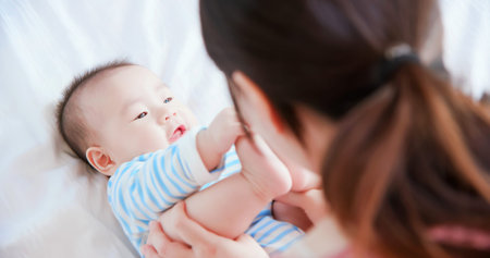 asian mother play with her baby on the bed