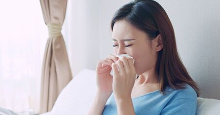 asian woman sick and sneeze with tissue paper in the bedroomの写真素材