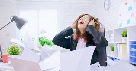 Business asian woman stressed and overworked yelling in office with rainy documentsの写真素材