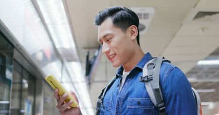 asian young man use 5g smartphone on the mrt station