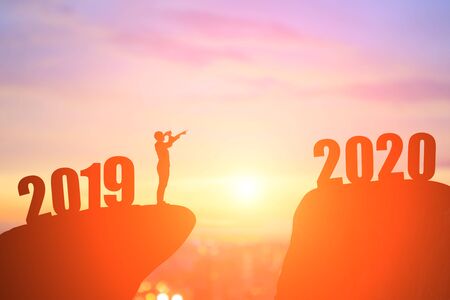 silhouette of businessman take binoculars and pointing 2020 on the mountainの写真素材