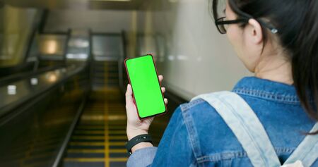 asian young woman use 5g full display smartphone on the escalatorの写真素材