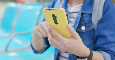asian young woman use yellow smartphone on the mrt station