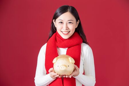 asian woman hold piggy bank and smile to youの写真素材