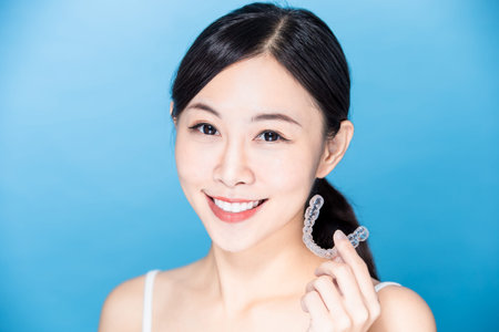 asian woman take her invisible brace on hand and smile to you