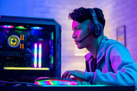 Young Asian Handsome Pro Gamer Playing in Online Cyber Sport Game at homeの写真素材