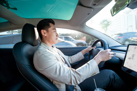 asian relaxed man is driving electric car