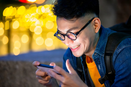 asian young man watch video on phone outdoor in the evening