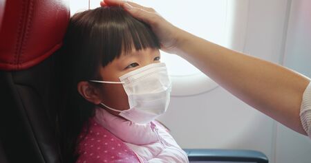 Asian parents wear masks to their children because of transmissible infectious diseases in the airplaneの写真素材
