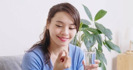 asian woman eat medicine pills to increase immunity with water and feel better at homeの写真素材
