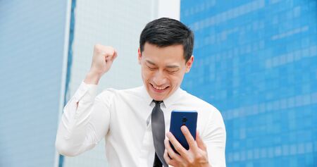 Successful  asian business man feel excited while looking the smartphoneの写真素材