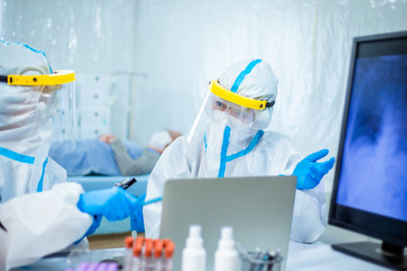 scientists studying xray of coronavirus patient lung on computer screen with the isolation gown or...